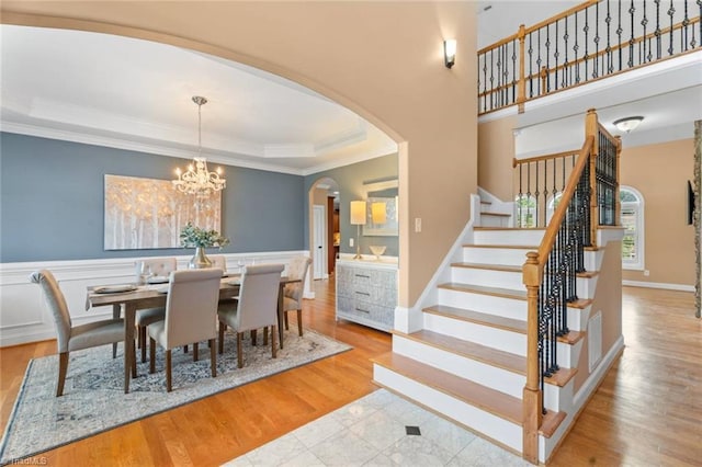 142 Covington Pl, Lewisville, NC 27023 - dining space with arched walkways, a raised ceiling, stairs, ornamental molding, and wood finished floors