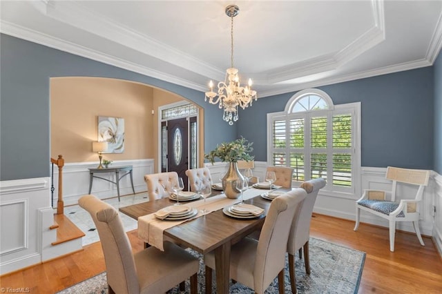 142 Covington Pl, Lewisville, NC 27023 - dining room with arched walkways, light wood-style flooring, a tray ceiling, a chandelier, and wainscoting
