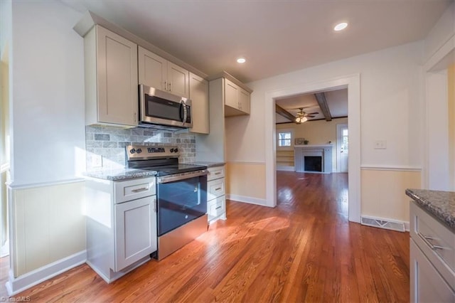 kitchen featuring light wood-type flooring, stainless steel appliances, light stone counters, and tasteful backsplash