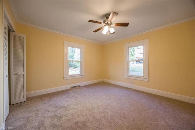 carpeted empty room featuring ceiling fan and crown molding