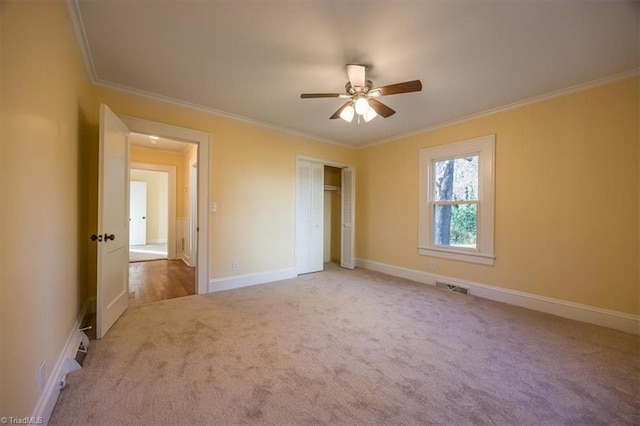 unfurnished bedroom with carpet floors, a closet, ceiling fan, and crown molding