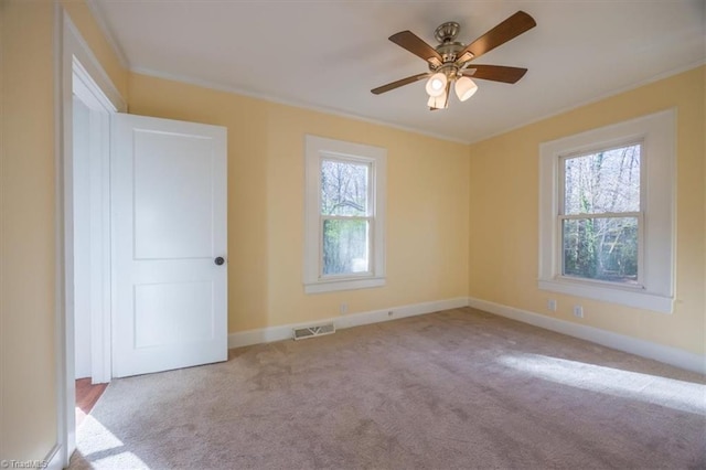 unfurnished room featuring light carpet, crown molding, ceiling fan, and a healthy amount of sunlight