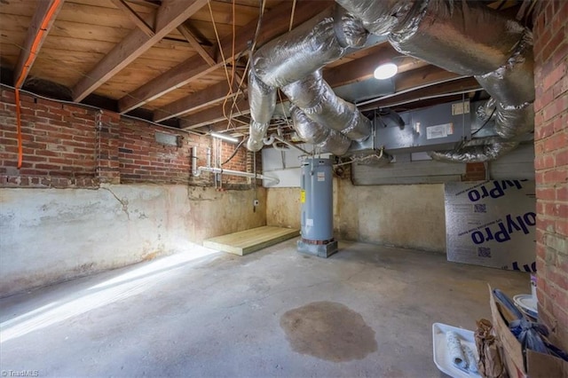 basement featuring electric water heater and brick wall