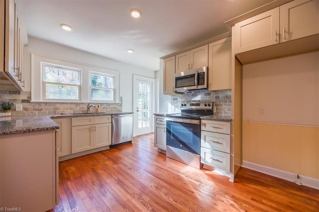 kitchen with backsplash, light hardwood / wood-style floors, sink, and stainless steel appliances