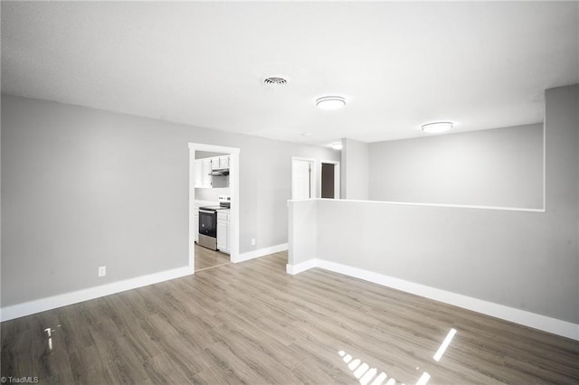 empty room featuring light wood finished floors, visible vents, and baseboards