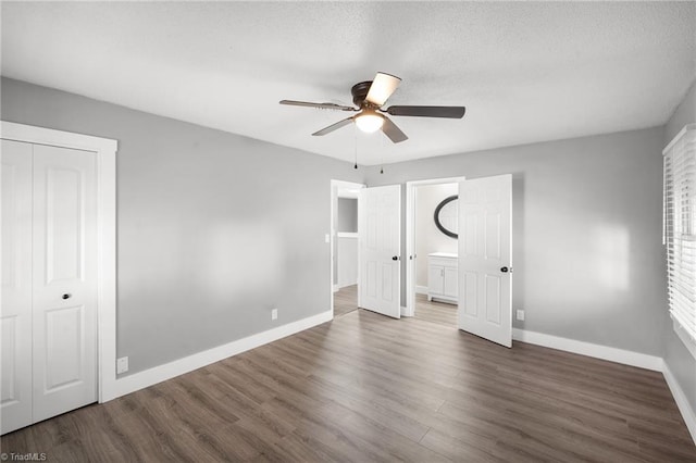 unfurnished bedroom featuring a textured ceiling, wood finished floors, and baseboards