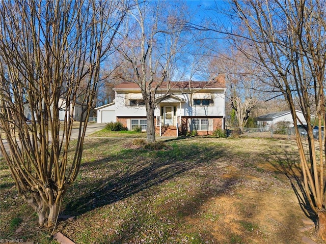 raised ranch with brick siding, a chimney, fence, a garage, and a front lawn