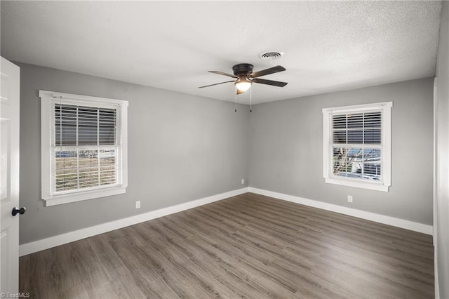 unfurnished room featuring a ceiling fan, baseboards, a wealth of natural light, and wood finished floors