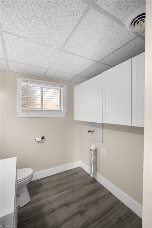 laundry room with dark wood-type flooring, visible vents, and baseboards