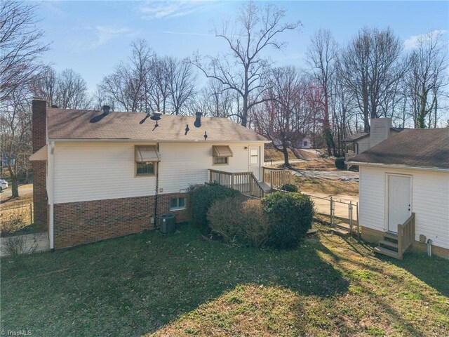 rear view of property featuring entry steps, a chimney, fence, a yard, and brick siding