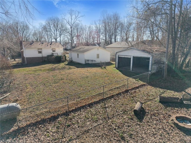 exterior space featuring a detached garage, fence, and an outbuilding