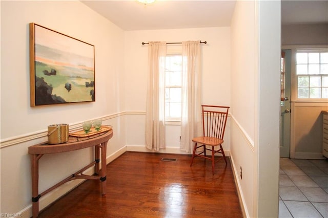 sitting room featuring baseboards, plenty of natural light, visible vents, and wood finished floors