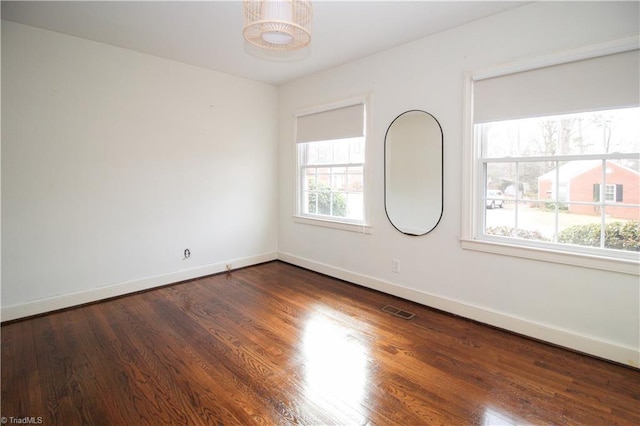 unfurnished room featuring dark wood-style floors, baseboards, and visible vents