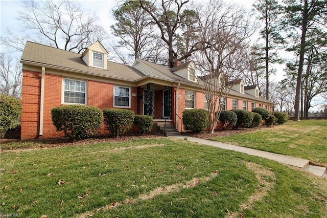 new england style home with a front yard and brick siding