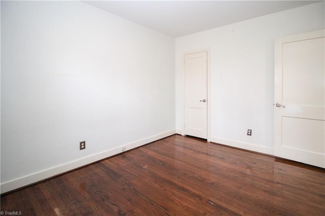 spare room featuring hardwood / wood-style flooring and baseboards