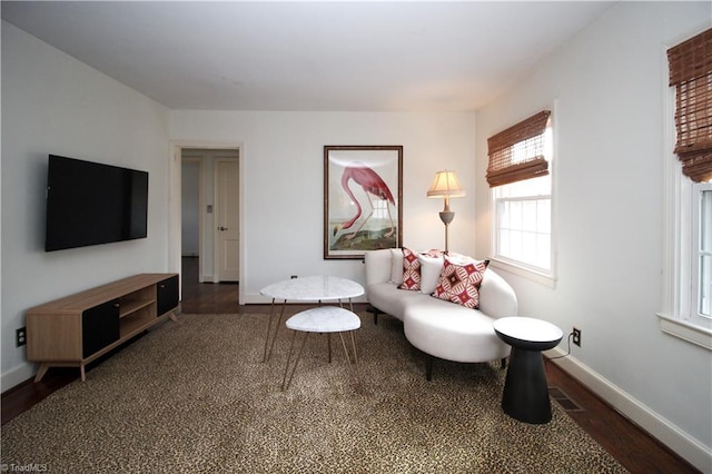 living area featuring visible vents, baseboards, and wood finished floors