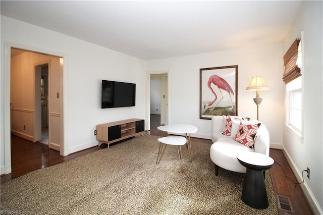 living room featuring visible vents, baseboards, and wood finished floors