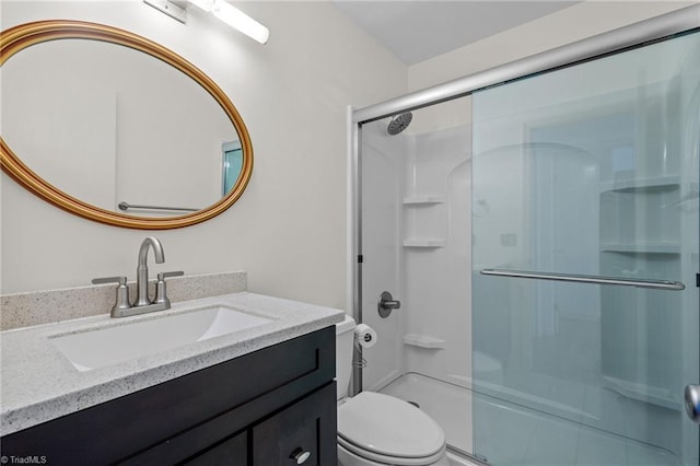 bathroom with vanity, a shower with door, and toilet