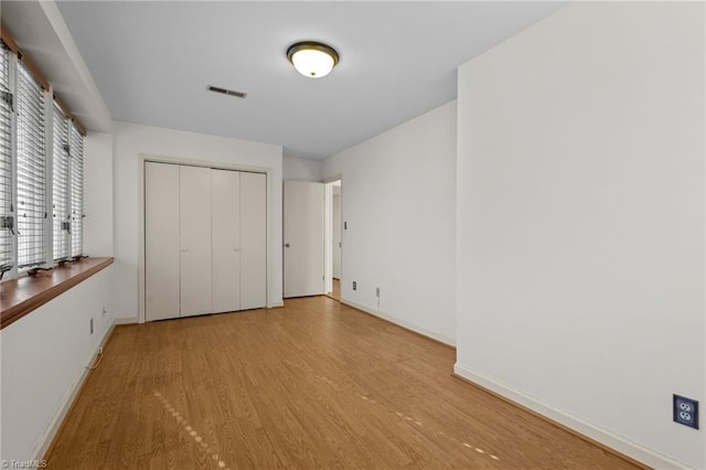 unfurnished bedroom with a closet and light wood-type flooring