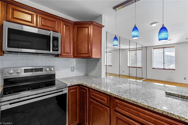 kitchen with tasteful backsplash, appliances with stainless steel finishes, decorative light fixtures, and light stone countertops