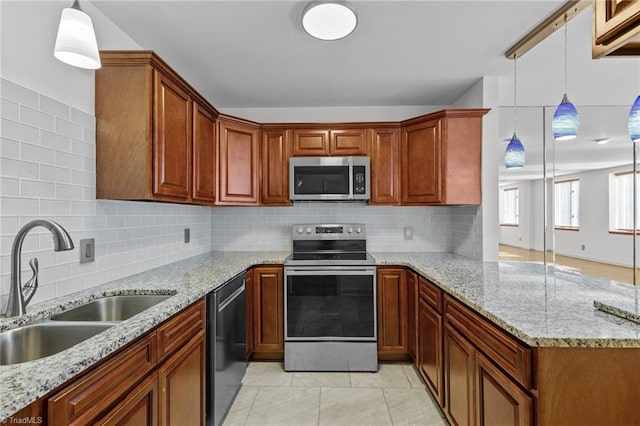 kitchen featuring pendant lighting, stainless steel appliances, sink, and light stone counters