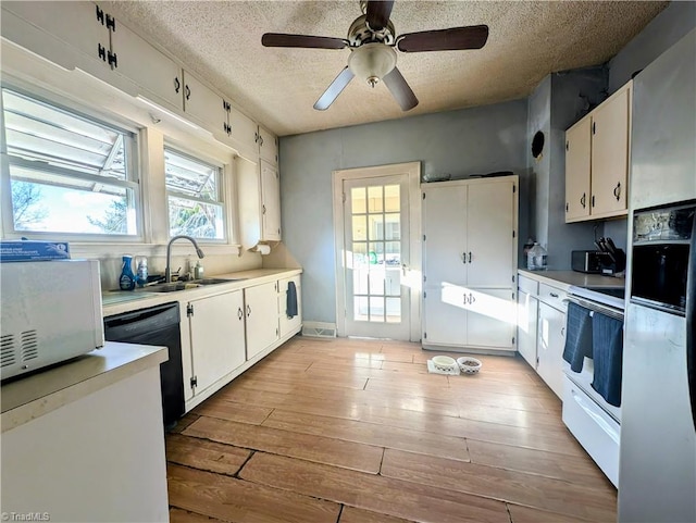 kitchen featuring white electric range oven, a textured ceiling, sink, light hardwood / wood-style flooring, and white cabinetry