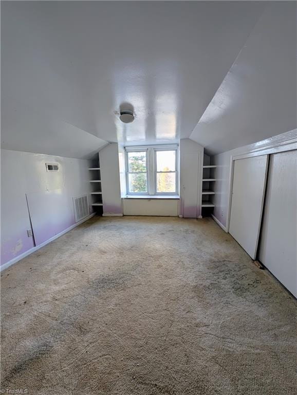 additional living space featuring carpet, built in shelves, and vaulted ceiling