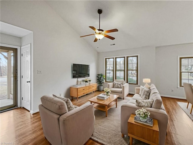 living room featuring light wood-type flooring, high vaulted ceiling, and a healthy amount of sunlight