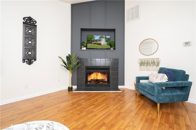 living room featuring wood-type flooring and a tile fireplace