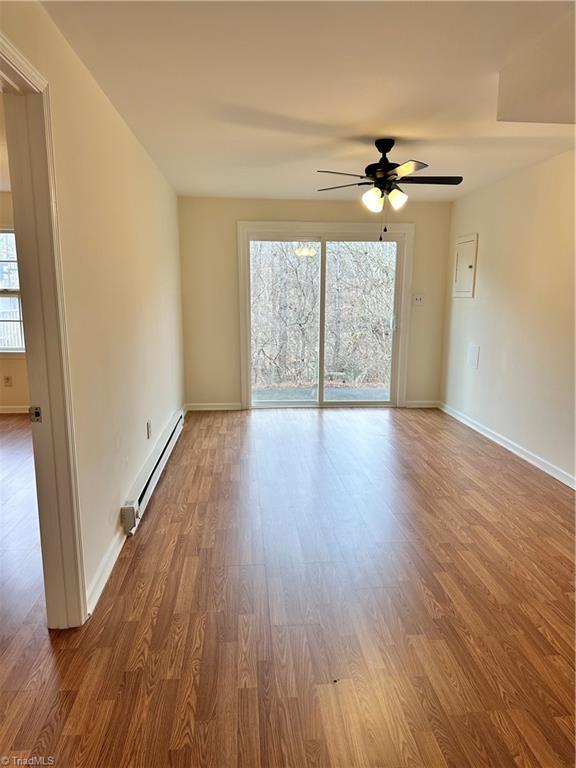 spare room with wood-type flooring, a baseboard heating unit, and ceiling fan