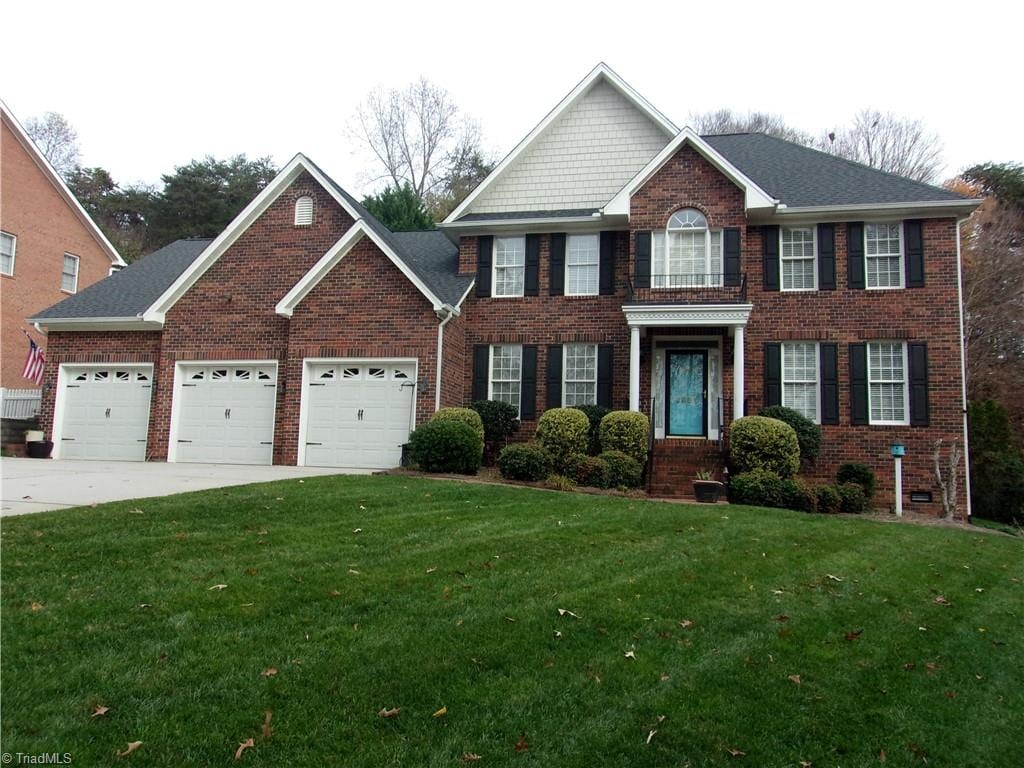 colonial home with a garage and a front lawn