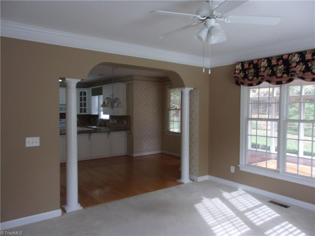 unfurnished dining area with ornate columns, crown molding, a healthy amount of sunlight, and light wood-type flooring