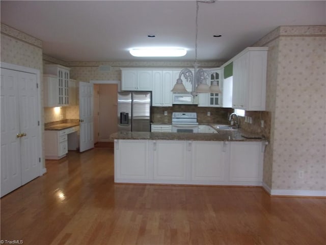 kitchen featuring light hardwood / wood-style flooring, kitchen peninsula, decorative light fixtures, white appliances, and white cabinets