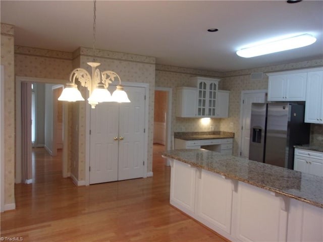 kitchen featuring white cabinets, hanging light fixtures, light wood-type flooring, stainless steel fridge with ice dispenser, and a chandelier