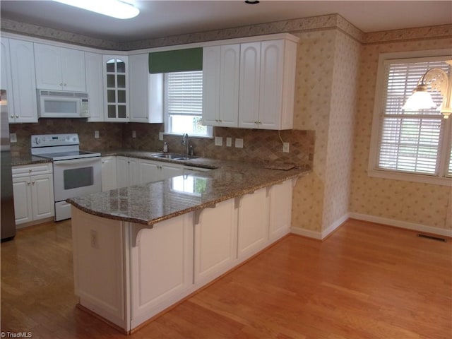 kitchen featuring kitchen peninsula, white cabinetry, sink, and white appliances