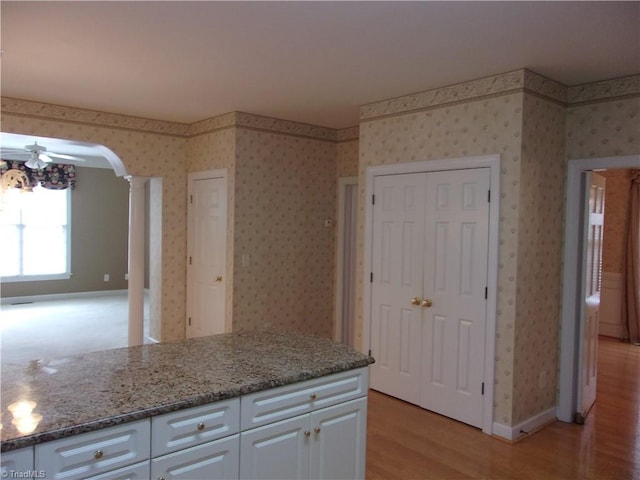 kitchen with ceiling fan, light stone countertops, ornate columns, light hardwood / wood-style floors, and white cabinetry