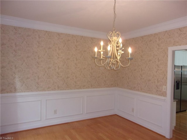 unfurnished dining area featuring light wood-type flooring, crown molding, and a chandelier