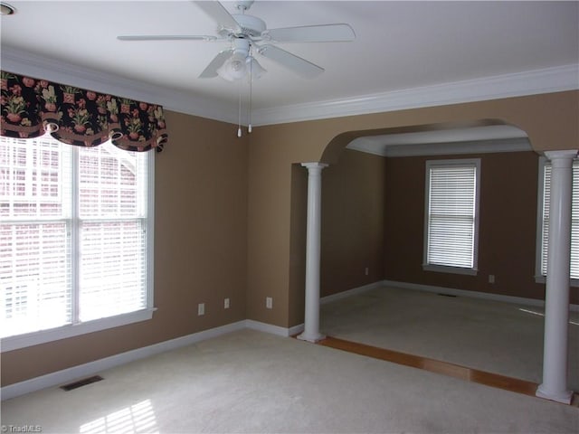 unfurnished room featuring decorative columns, ceiling fan, carpet floors, and ornamental molding