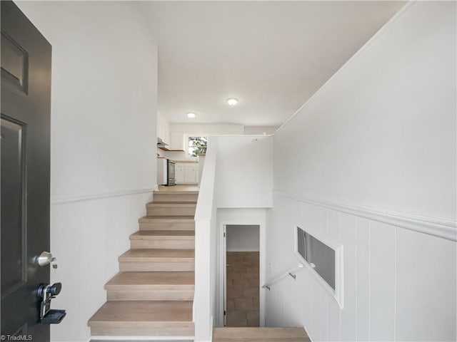 stairs featuring a wainscoted wall