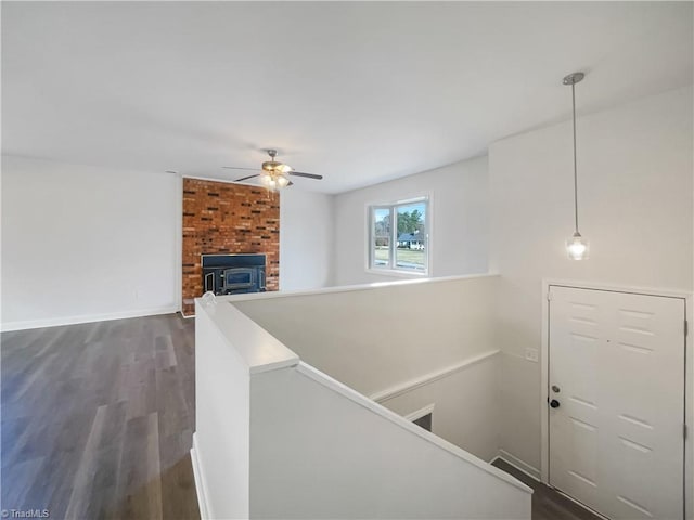 corridor with dark wood-style floors, baseboards, and an upstairs landing