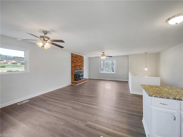 unfurnished living room featuring ceiling fan, dark wood-type flooring, visible vents, and baseboards