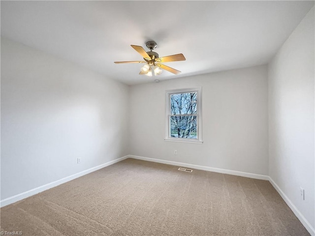 carpeted empty room featuring baseboards, visible vents, and a ceiling fan