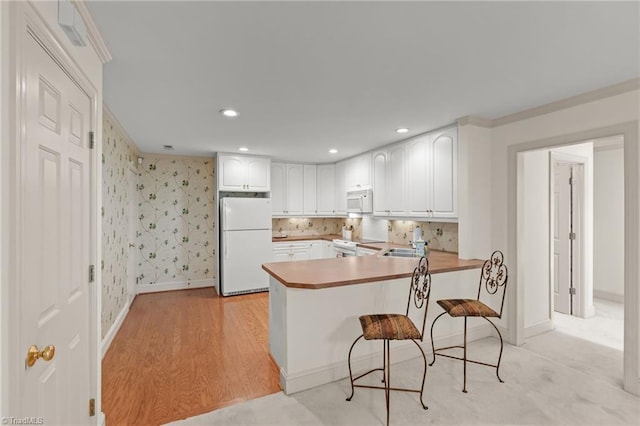 440 Marshall View Ct, Winston-Salem, NC 27101 - kitchen with white appliances, a peninsula, a kitchen bar, white cabinetry, and wallpapered walls