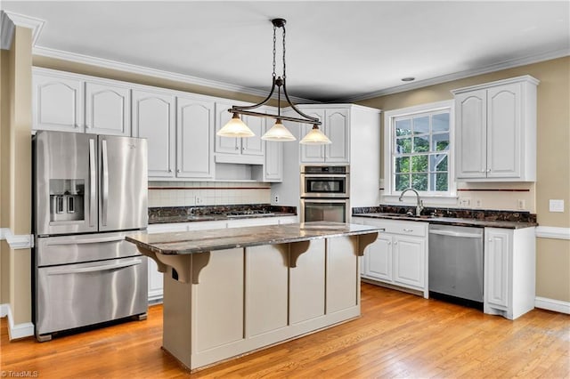 kitchen featuring appliances with stainless steel finishes, a sink, dark stone counters, a kitchen bar, and ornamental molding