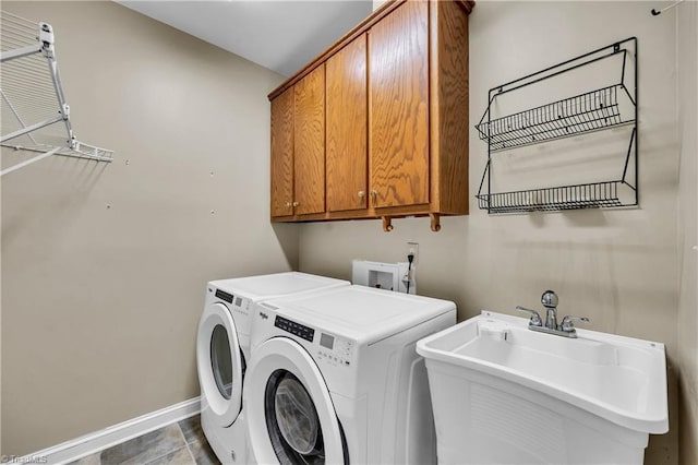 clothes washing area featuring cabinet space, independent washer and dryer, and baseboards