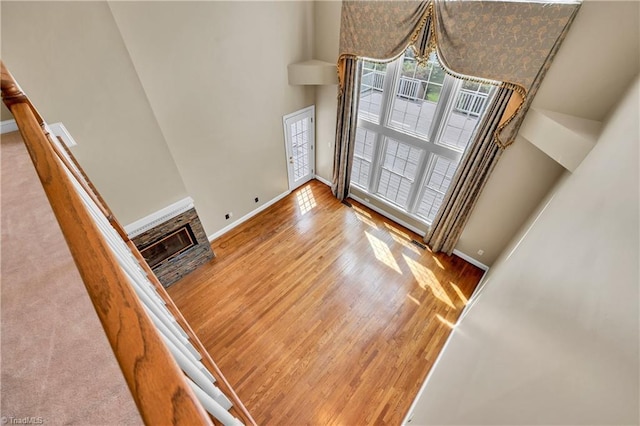 unfurnished dining area featuring wood finished floors, baseboards, a towering ceiling, and a fireplace