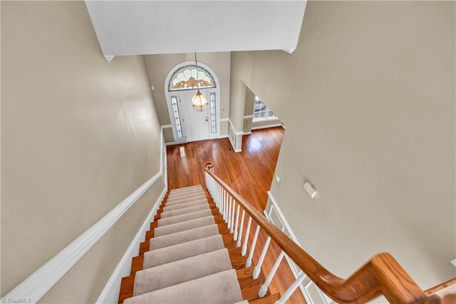 stairs with wood finished floors, baseboards, and a high ceiling