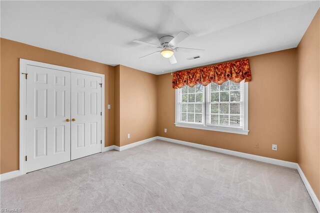 unfurnished bedroom featuring carpet flooring, a closet, baseboards, and ceiling fan