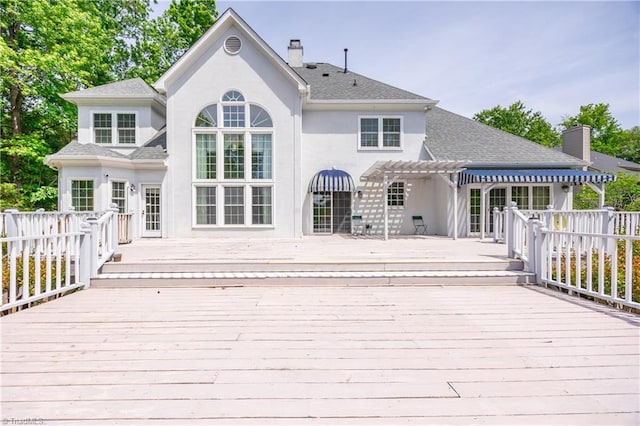 back of property featuring stucco siding, a pergola, a chimney, and a deck