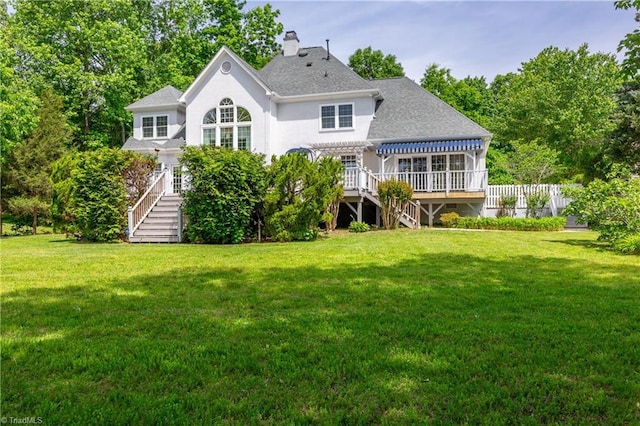 rear view of property featuring stairway, a deck, a yard, and a chimney